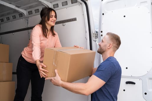 Zwei Menschen laden Umzugskarton aus Transporter aus
